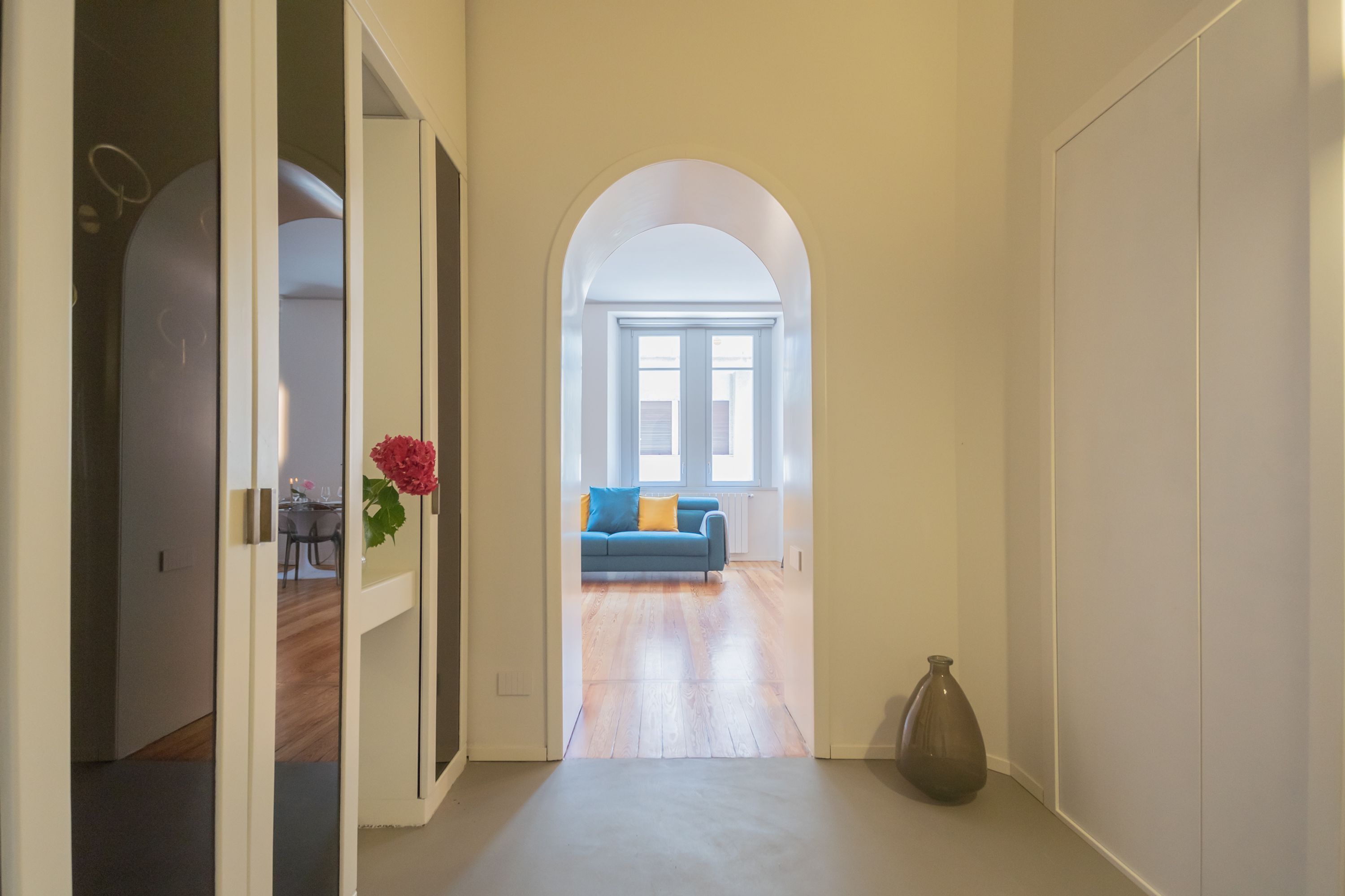 A hallway leading to a living area with a sofa and a vase.