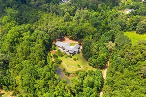 An aerial view of a house surrounded by dense forest, with a small pond and a well-maintained lawn. - Secluded Spiritual Oasis in Travelers Rest (Travelers Rest)