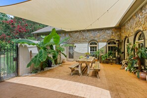 A covered patio area with a stone wall, arched windows, and potted plants. - Secluded Spiritual Oasis in Travelers Rest (Travelers Rest)