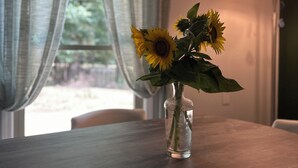 A clear view of a room with a table, a vase with sunflowers, a window with curtains, and a lamp. - Secluded Spiritual Oasis in Travelers Rest (Travelers Rest)