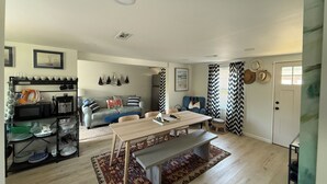 A spacious living area with a dining table, sofa, and a kitchen area with a microwave and coffee maker.