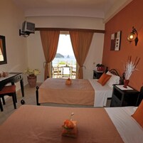 Habitación de hotel con dos camas, un escritorio, una silla, un televisor y vista al mar.