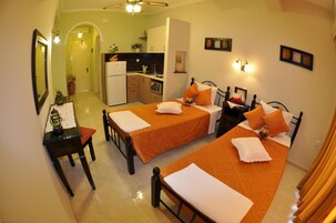 Habitación de hotel con dos camas, un escritorio, una silla, kitchenette y baño.