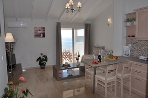 Habitación de hotel con comedor, vista al mar y kitchenette.