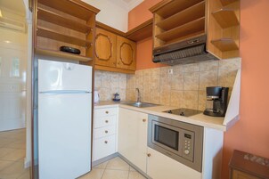 Una cocina compacta con microondas integrado, cafetera y refrigerador.