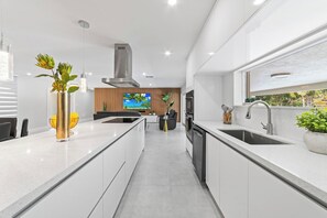 Cozinha moderna com ilha central, forno embutido e uma janela grande.