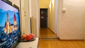 A hotel room with a television displaying a cityscape, a remote control, and decorative items on a table. - Neri 33 in Firenze With 3 Bedrooms and 2 Bathrooms (Florence)