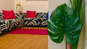 A living room with a black and white patterned sofa, red cushions, a red rug, and a large green plant. - Neri 33 in Firenze With 3 Bedrooms and 2 Bathrooms (Florence)