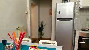 A kitchen with a refrigerator, oven, and a dining table with a tray of food and a bag of snacks. - Neri 33 in Firenze With 3 Bedrooms and 2 Bathrooms (Florence)