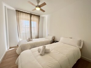 A hotel room with two beds, a ceiling fan, and a window with curtains. - Alq 305 Calalga Apartment (Calpe)