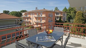A balcony with a table, chairs, and a fruit bowl.