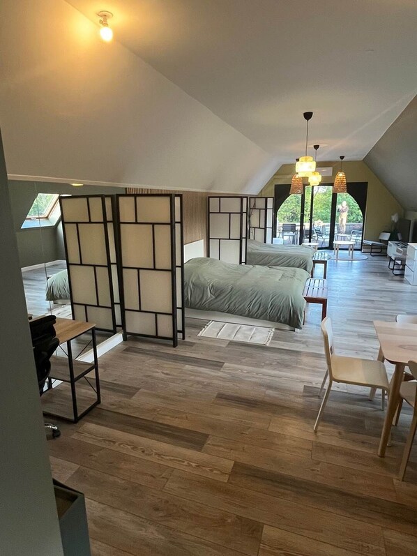 Et rummeligt loftværelse med en stor seng, et skrivebord og et spiseområde.