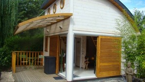 Una casa moderna con techo curvo, una terraza de madera y un amplio portón corredero.