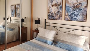 Une chambre à coucher avec un lit, une table de chevet, une lampe et deux tableaux accrochés au mur.