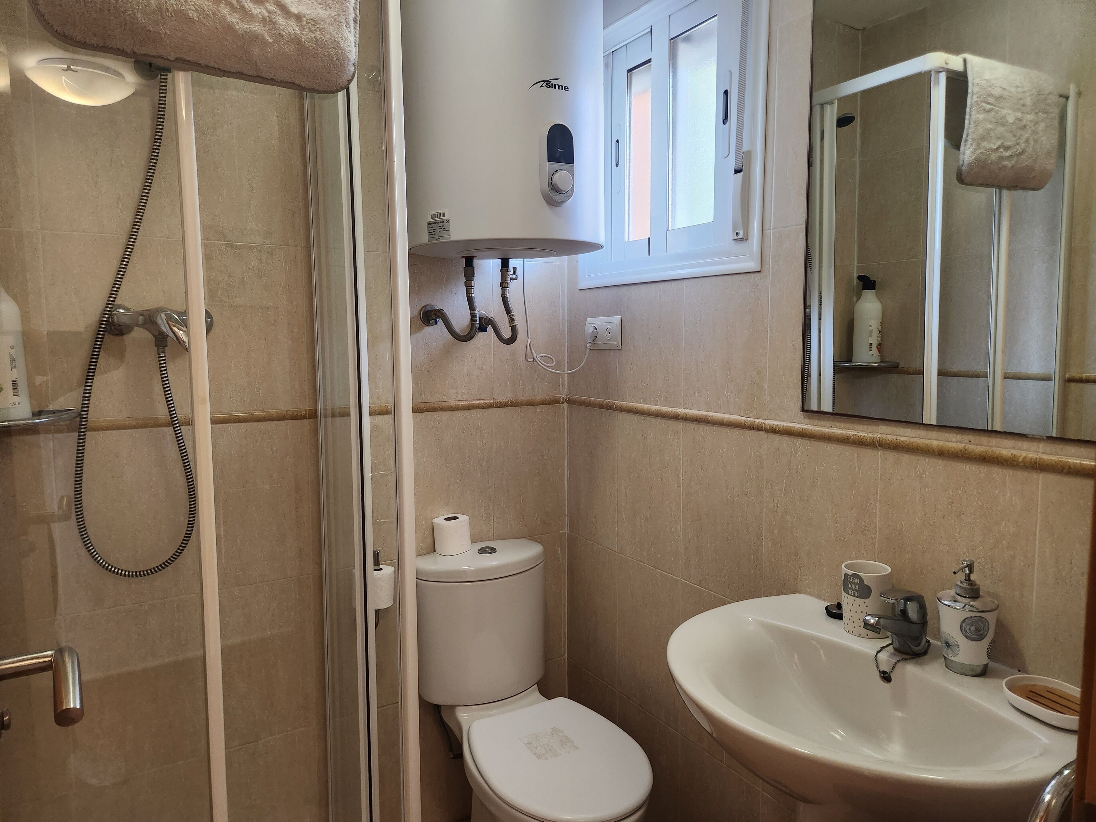A bathroom with a shower, toilet, sink, and a mirror.