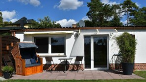 A patio area with a wicker sofa, a table, and chairs. - Spreeblick vacation apartment directly on the old Spree with lots of nature and relaxation (Grünheide)
