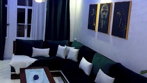Un salon moderne avec un canapé d’angle, une table basse et trois œuvres d’art encadrées accrochées au mur.