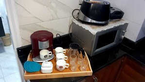 Un comptoir de cuisine avec une machine à café, un grille-pain et un plateau contenant des tasses et des verres.
