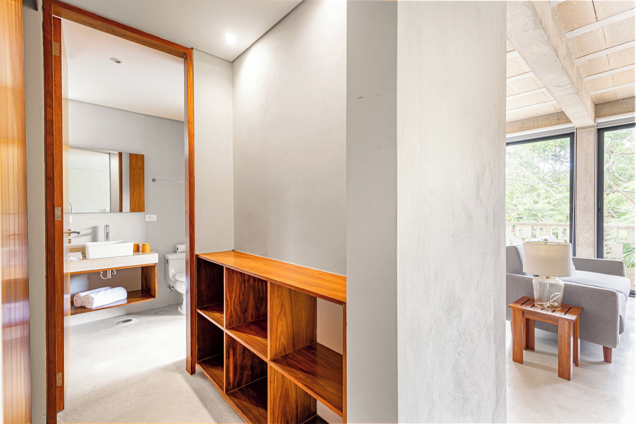 A modern bathroom with a wooden vanity, a large mirror, and a view of the outdoors through a window.