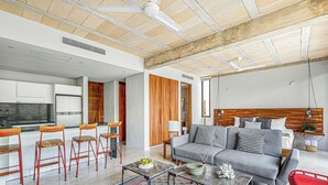 Una sala de estar moderna con un sofá gris, sillas rojas, una mesita de centro y una alfombra estampada.