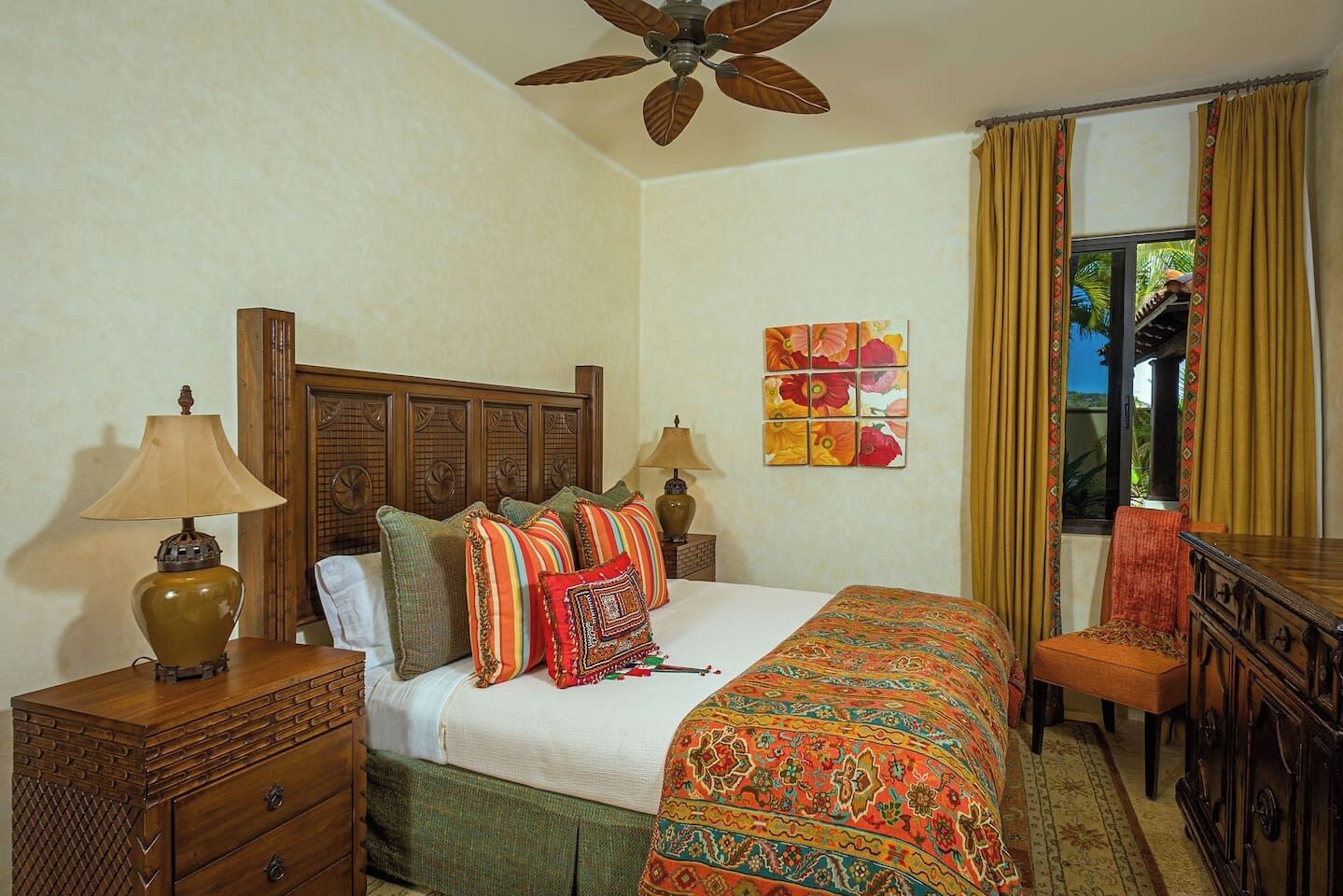 A well-furnished bedroom with a wooden headboard, a bed with multiple pillows, a nightstand with a lamp, a dresser, and a window with curtains.