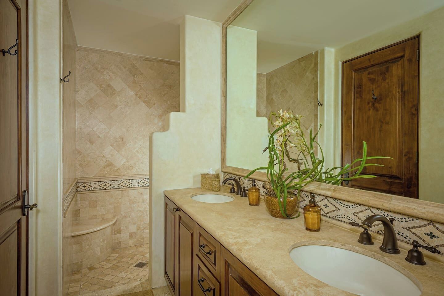 Une salle de bain avec deux lavabos, un grand miroir et un espace douche.