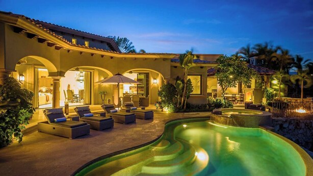 A luxurious outdoor pool area with sun loungers and a well-lit patio.