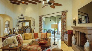 A spacious living room with a high ceiling, a fireplace, and a large window.