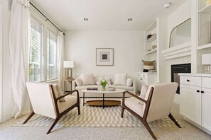 A living room with a sofa, two armchairs, a coffee table, and a fireplace. - Stylish 3 Bedroom Family Home (Beaverton)