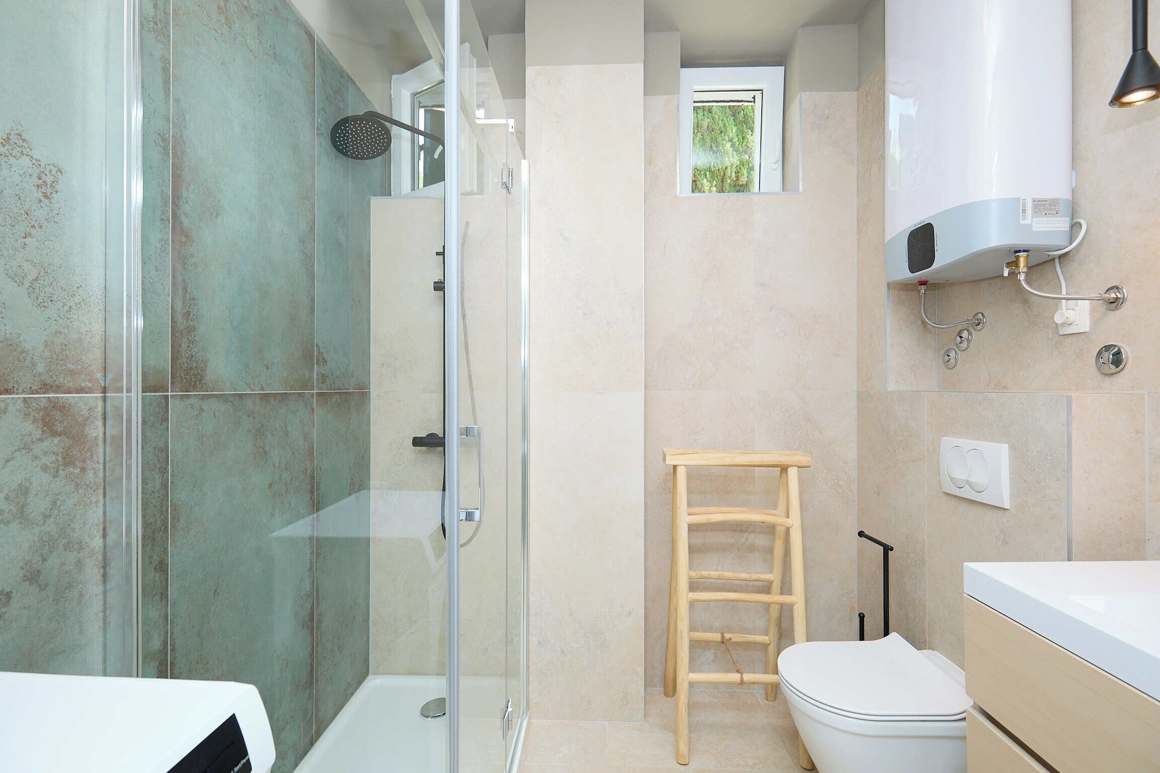 Une salle de bain moderne avec une douche à parois de verre, une échelle en bois, des toilettes blanches et un radiateur encastré.
