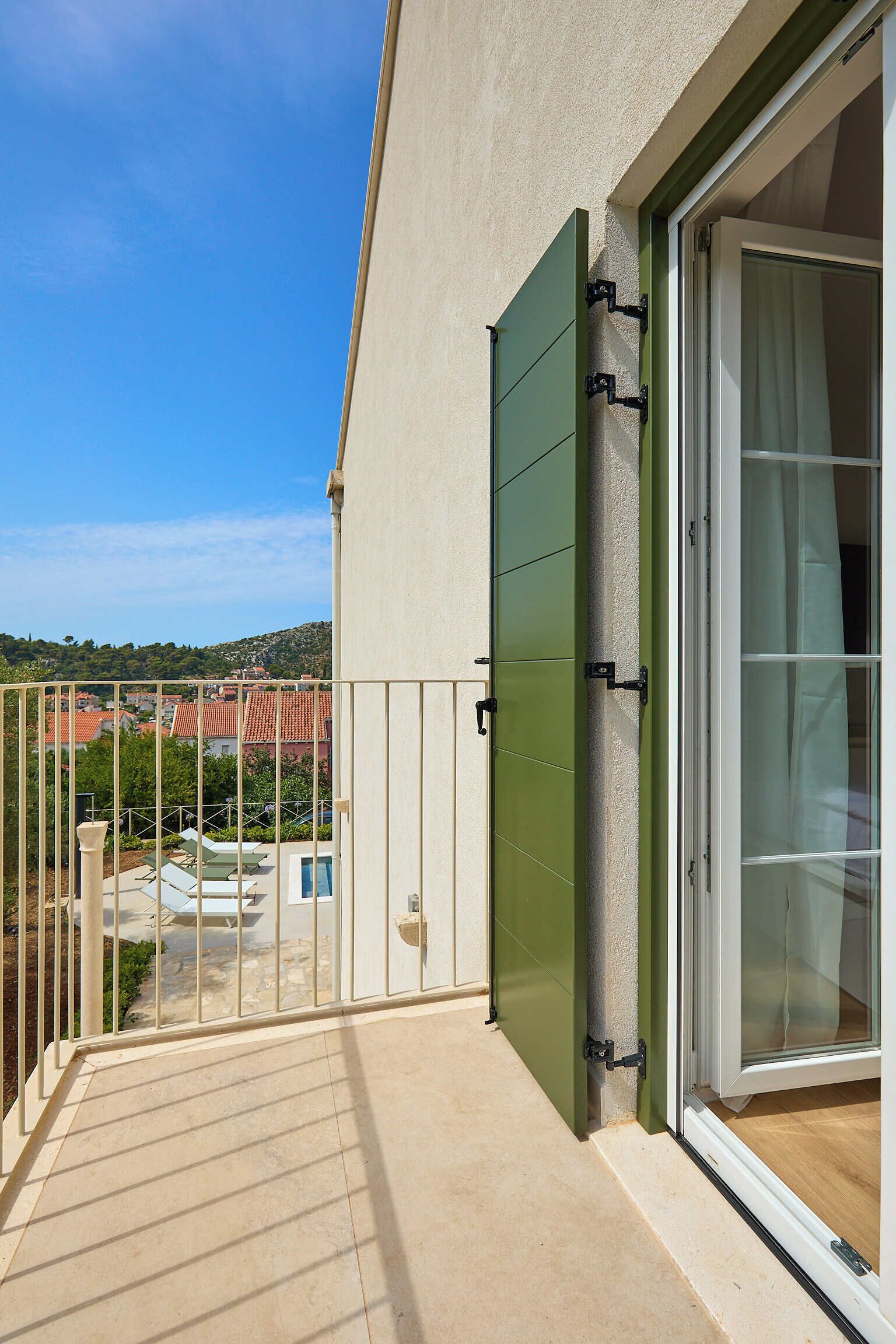 Un balcón con vistas a una zona residencial, una puerta corrediza y un pequeño espacio de estar al aire libre.
