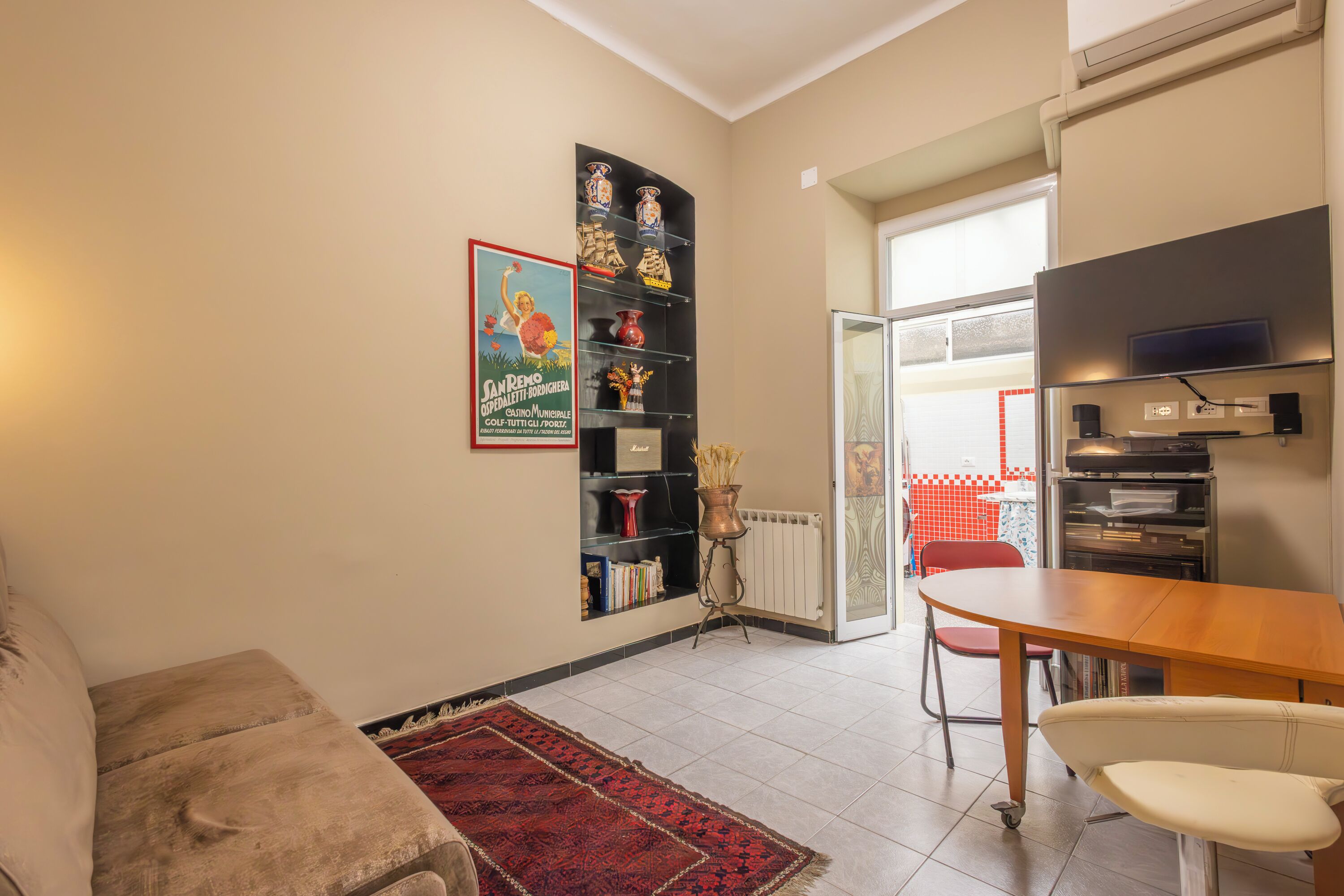 Una sala de estar con sofá, una mesa de comedor y una estantería.