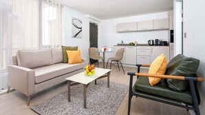 A modern living room with a sofa, a coffee table, and a dining area with chairs. - Micklegate by Supercity Aparthotels (York)