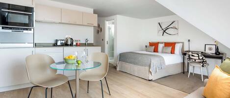 A compact apartment with a kitchenette, a dining area, and a bedroom.