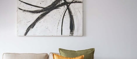 A living room with a sofa, a coffee table with lemons, and a large abstract painting on the wall.