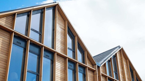 Un edificio moderno con grandes ventanales y paneles de madera.