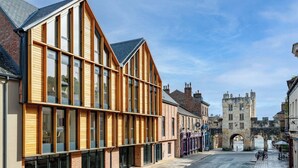 A street with modern buildings, a historic stone tower, and a cobblestone street. - Micklegate by Supercity Aparthotels (York)