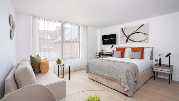 A modern bedroom with a bed, a sofa, a TV, and a window. - Micklegate by Supercity Aparthotels (York)
