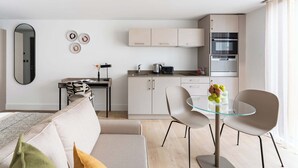 Una sala de estar moderna con un sofá, una mesa de centro de vidrio y un comedor con sillas y una pequeña mesa.