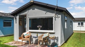A small, single-story house with a large window and two wicker chairs outside. - Seaglass Chalet - UK47636 (Mundesley, near North Walsham)