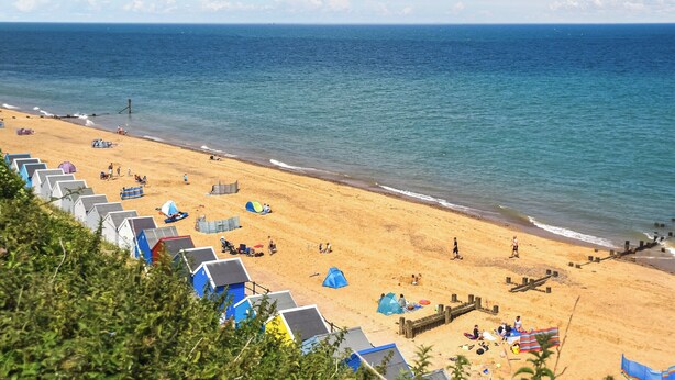 A beach with rows of colorful beach huts, a sandy shore, and the ocean. - Seaglass Chalet - UK47636 (Mundesley, near North Walsham)