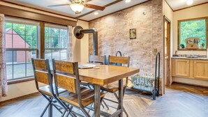 A dining area with a wooden table and chairs, a ceiling fan, and a brick wall. - 4 Mi to Lake Francis: Peaceful Pittsburg Home (Pittsburg)