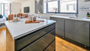 Une cuisine moderne dotée d’un grand îlot central, de planchers en bois et offrant une vue sur la ville.