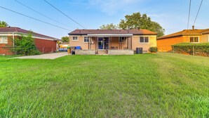 Ein zweistöckiges Haus mit Veranda, kleinem Vorgarten und Backsteinfassade.