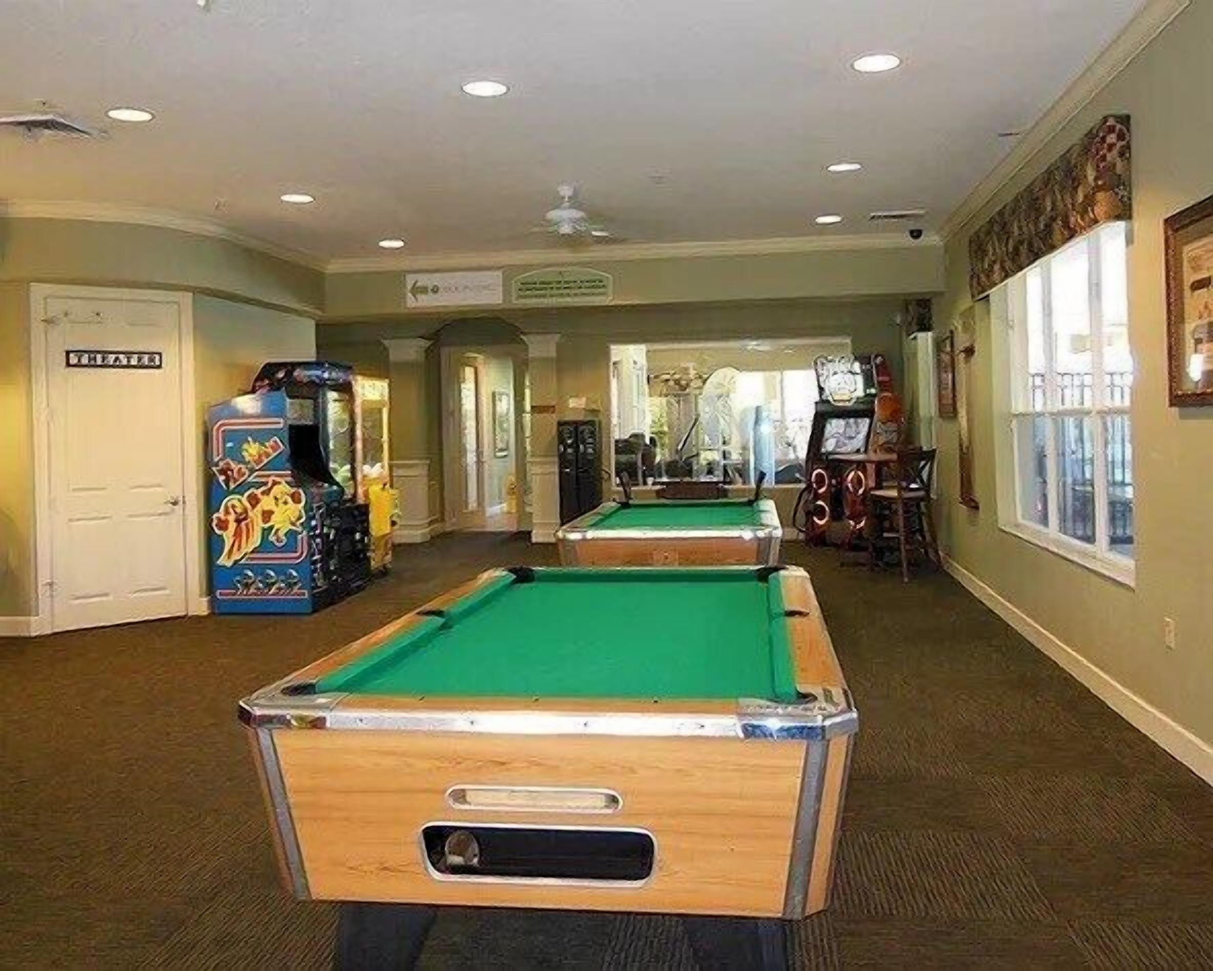 A pool table in a room with arcade games and a door labeled "SILVER."