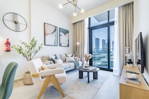 A modern living room with a sofa, armchair, coffee table, and artwork on the walls.