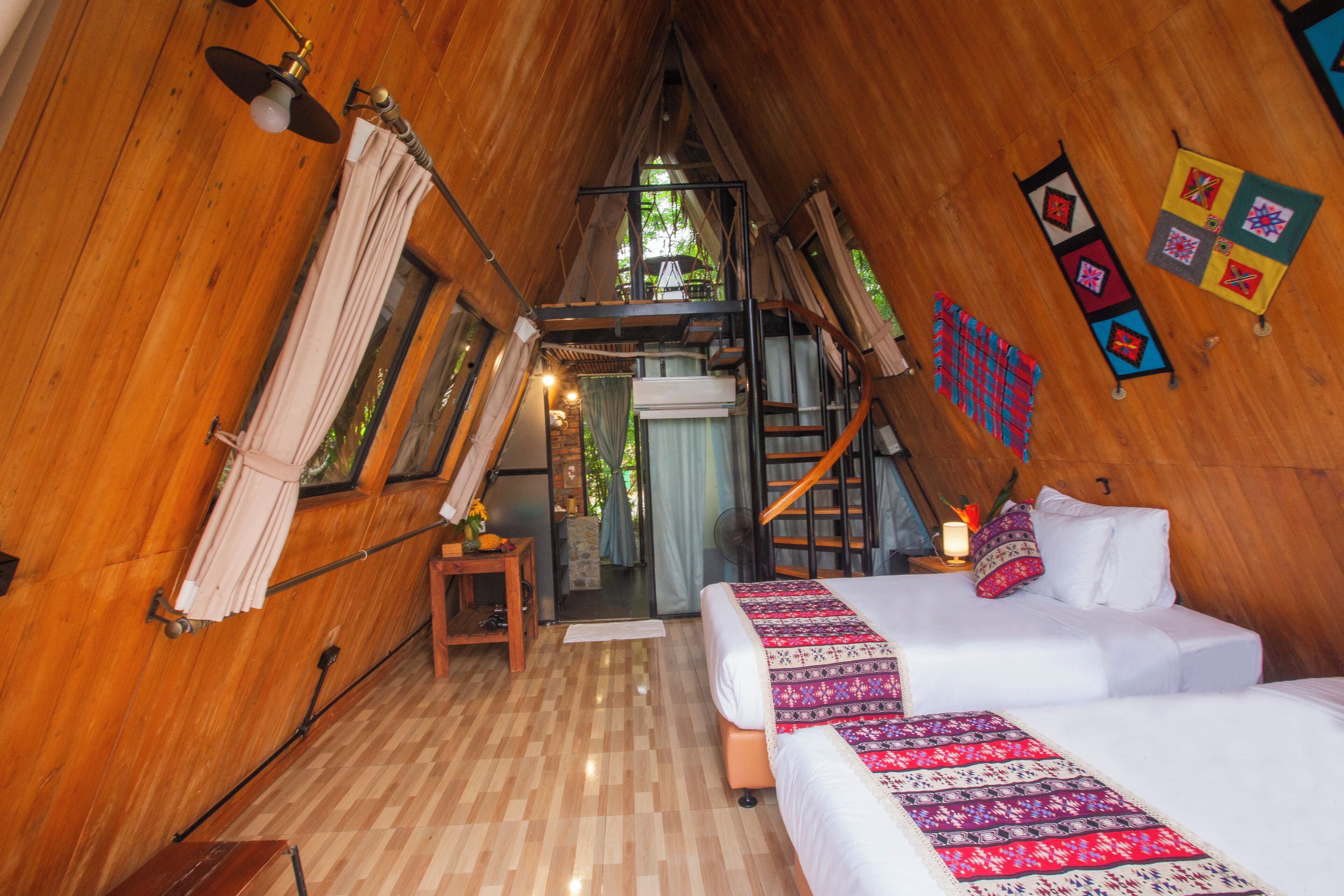 A wooden cabin bedroom with a loft bed, a small table, and a ladder.
