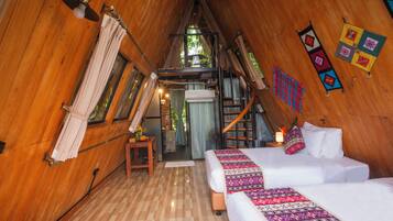 A wooden cabin bedroom with a loft bed, a small table, and a ladder.