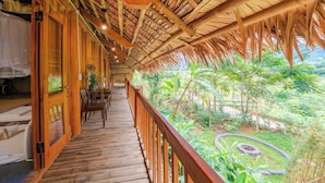 Una terraza de madera con techo de paja que da a un exuberante jardín.