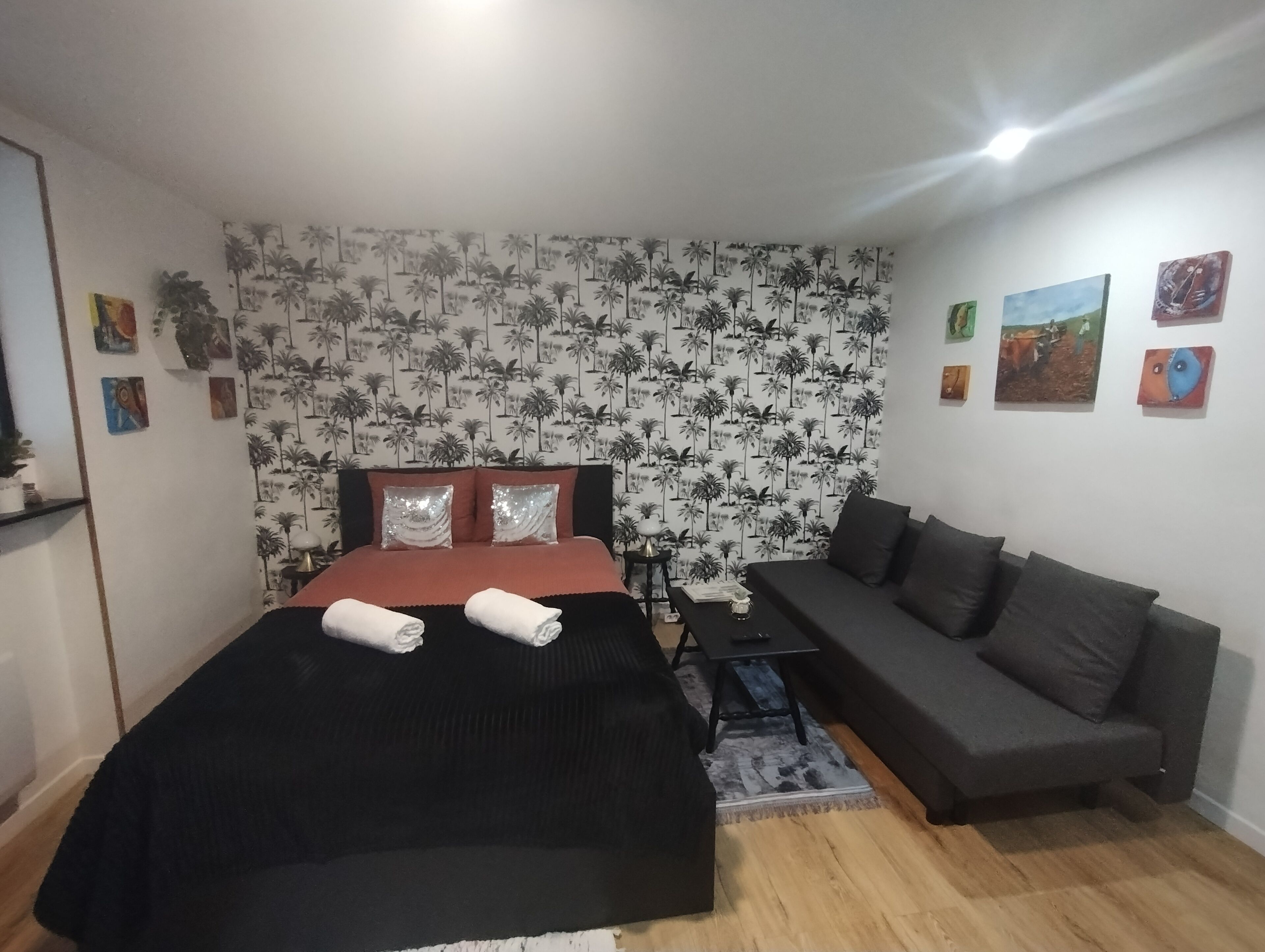Un dormitorio con cama, sofá y papel tapiz estampado.